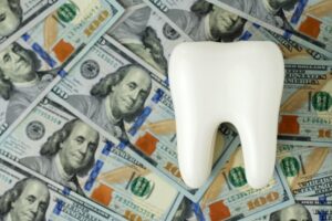 tooth model with $100 bills in the background