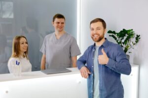 patient standing at the front desk with a thumbs up