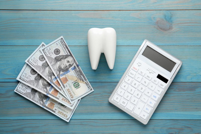 money, tooth, and calculator on a desk