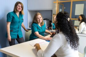 patient talking to two smiling dental team members