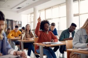 smiling student in a classroom raising her hand