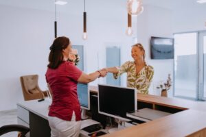 patient shaking hands with front desk dental team member